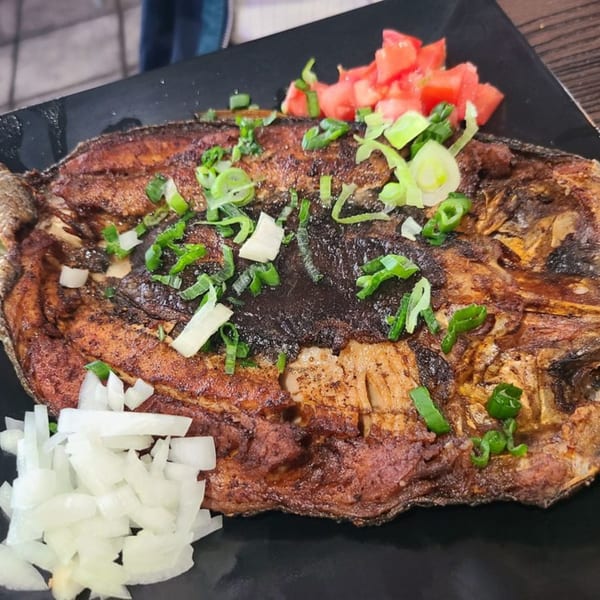 Grilled Filipino milkfish (bangus) topped with chopped tomatoes, green onions, and white onions.