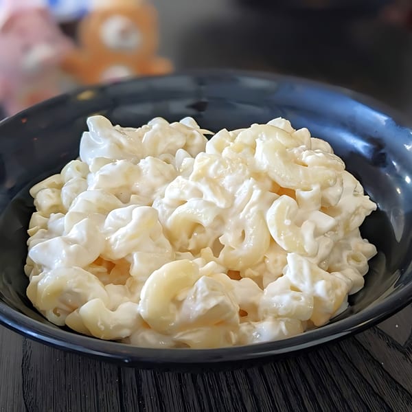 A black bowl filled with creamy Filipino macaroni salad, featuring elbow pasta in a rich white sauce.