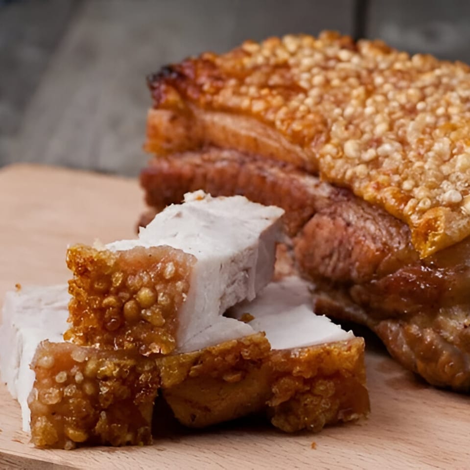 Crispy Filipino lechon kawali, a deep-fried pork belly dish, on a wooden cutting board.